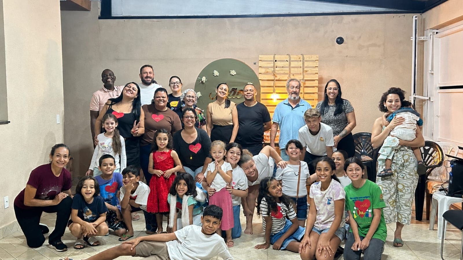Célula reunida na sala de uma casa: adultos em pé ao fundo e as crianças sentadas no chão à frente