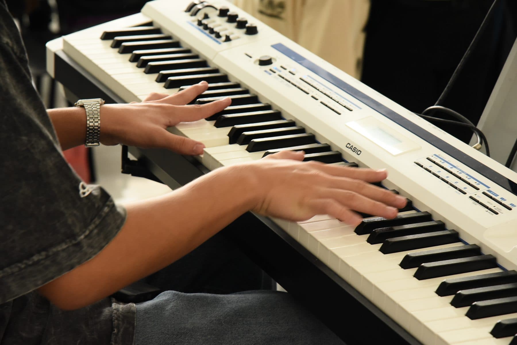 Close das duas mãos de alguém tocando um teclado branco durante o louvor de uma célula