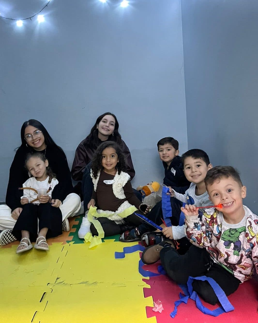 Célula de crianças reunida no chão de uma sala, com as líderes