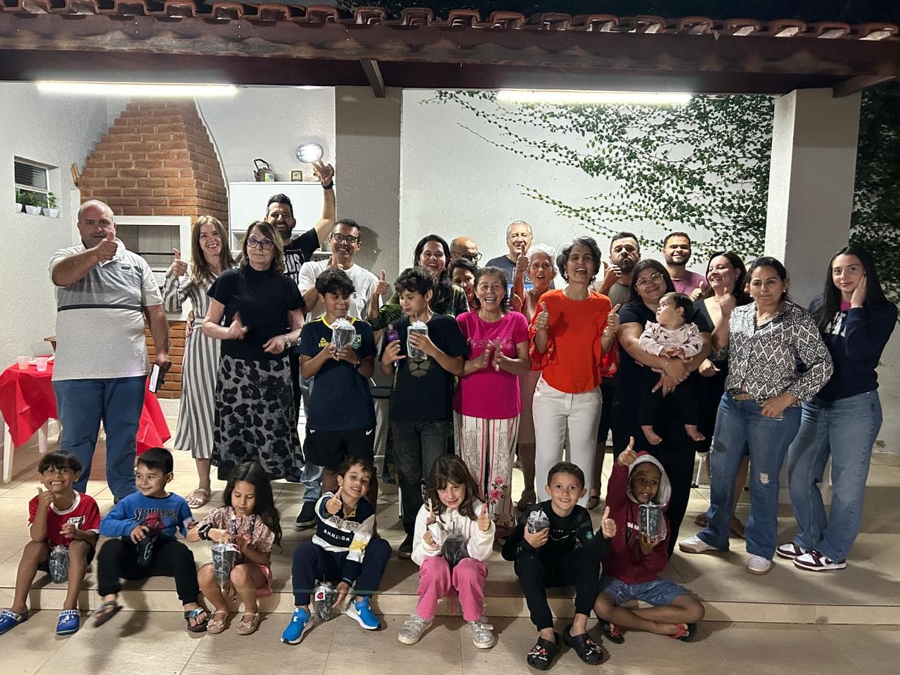 Célula reunida na varanda de uma casa: adultos, jovens e crianças posando juntos no fim do encontro
