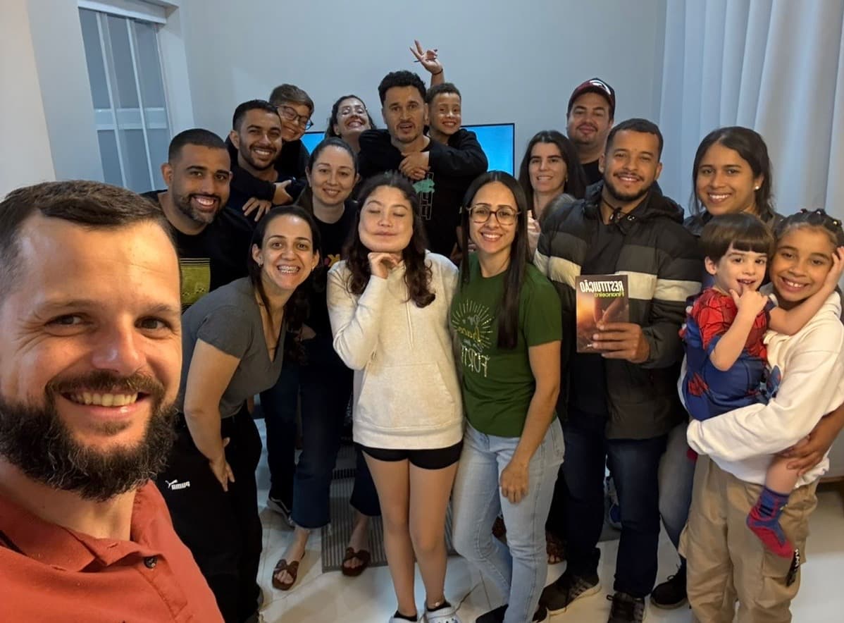 Célula reunida na sala de uma casa, adultos e crianças posando juntos para a foto