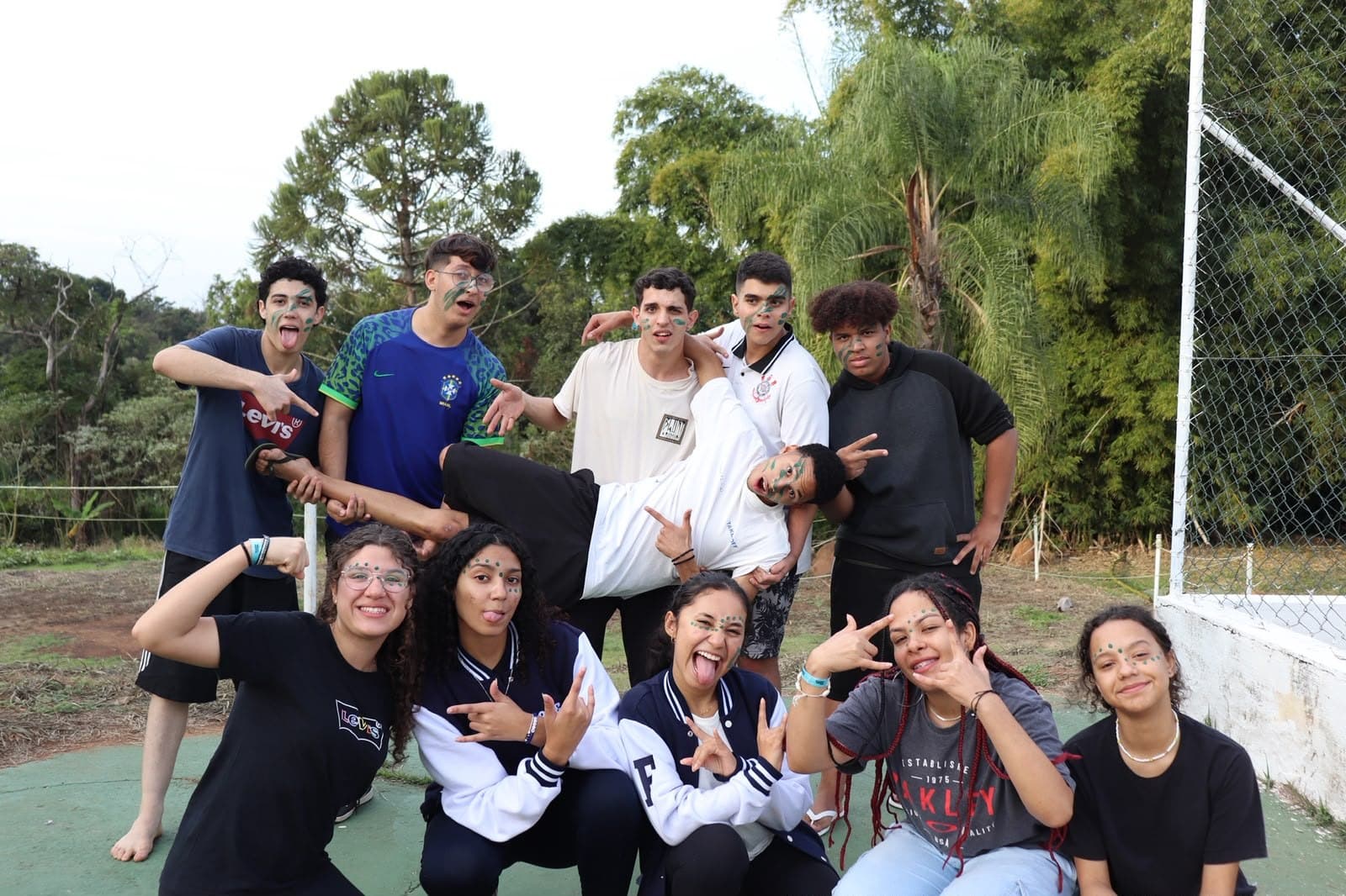 Turma de jovens dos Radicais Livres reunida em poses descontraídas em quadra poliesportiva