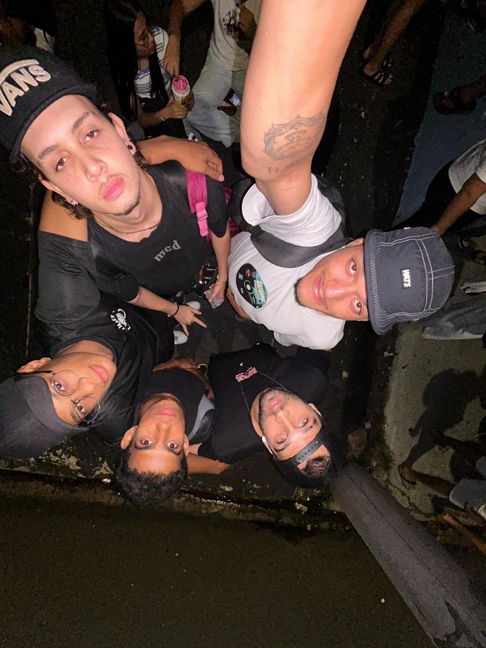 Roda de jovens vista de baixo, os rostos debruçados sobre a câmera no escuro